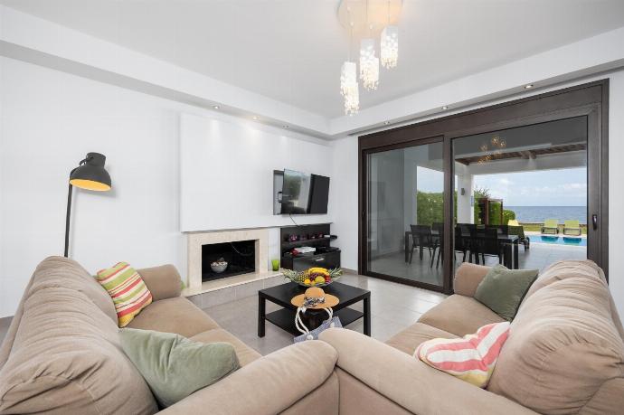 Open-plan living room with sofas, dining area, kitchen, ornamental fireplace, A/C, WiFi internet, satellite TV, and sea views . - Villa Metis . (Photo Gallery) }}