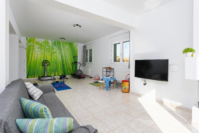 Living area with sofa, gym area, kitchen, and satellite TV . - Villa Sonata . (Photo Gallery) }}