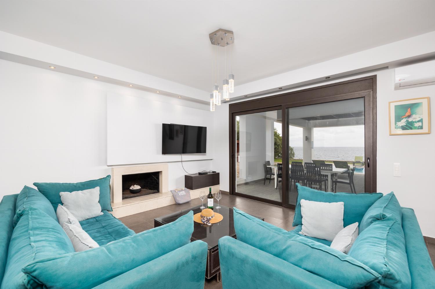 Open-plan living room with sofas, dining area, kitchen, ornamental fireplace, A/C, WiFi internet, satellite TV, and sea views