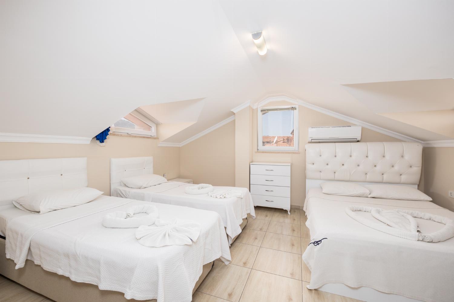 Bedroom with double bed and two single beds, en suite bathroom, and A/C