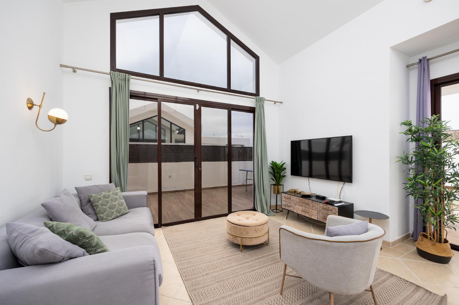 Living room with sofa, dining area, A/C, WiFi internet, and satellite TV